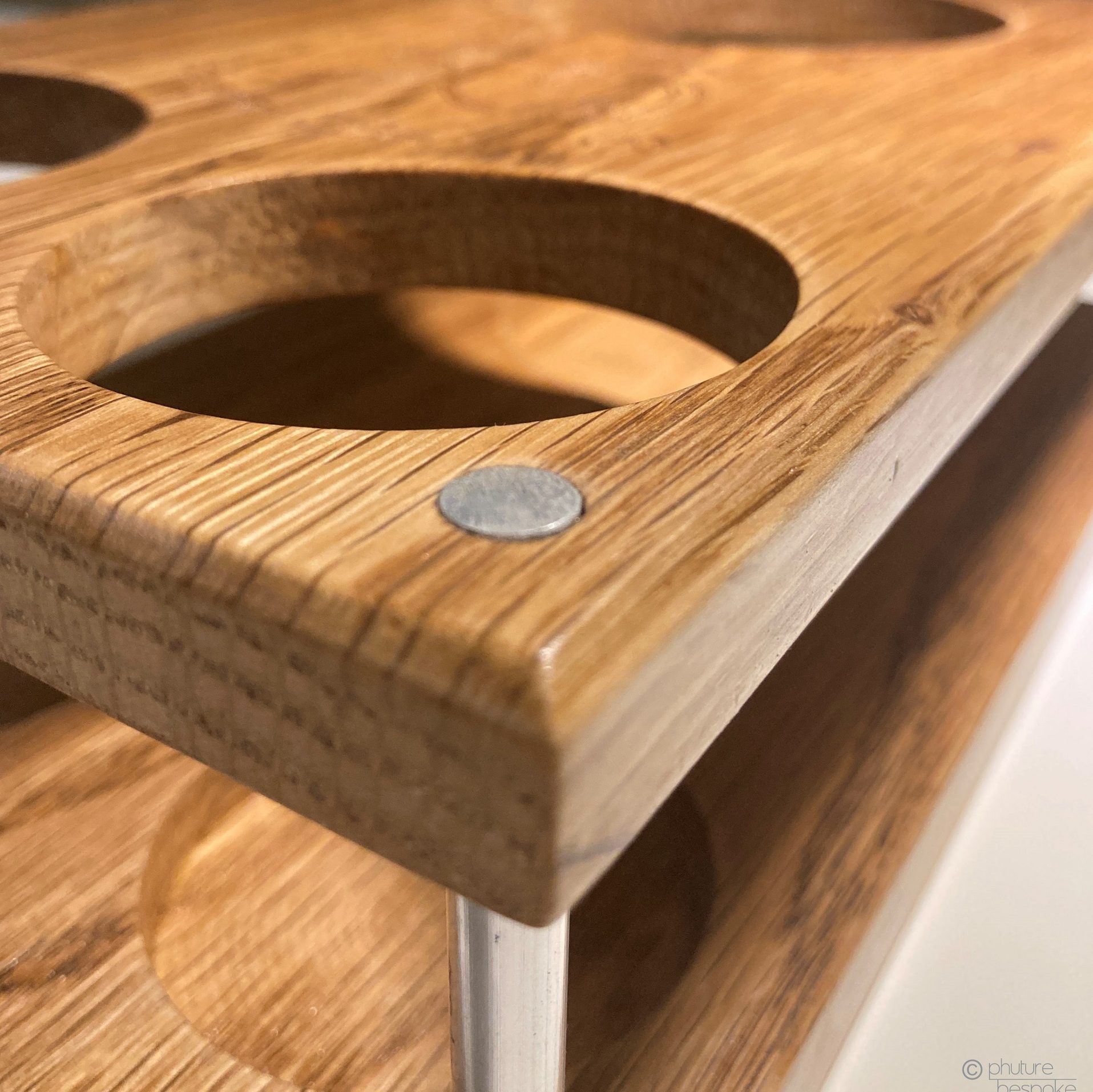 A close corner view of an oak gin set with aluminium risers. Links to the corresponding product page