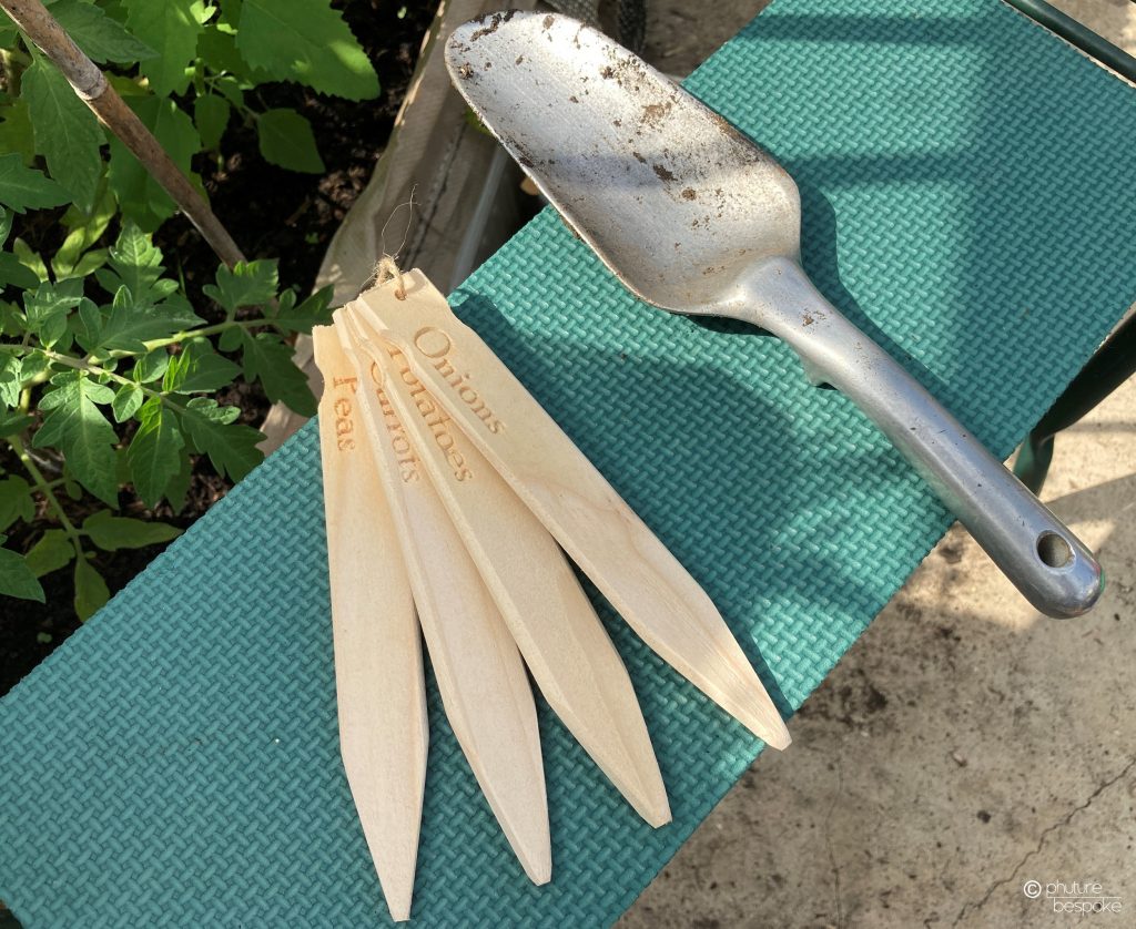 4 wooden engraved plant markers with a metal trowel. Links to the corresponding product page