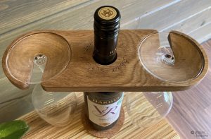 An engraved oak wine glass hanger on a bottle of wine with glasses hanging. Links to the corresponding product page